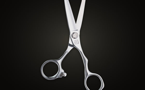 Chromium cutting shear with blades open showing the hand-honed convex edge, on onyx
